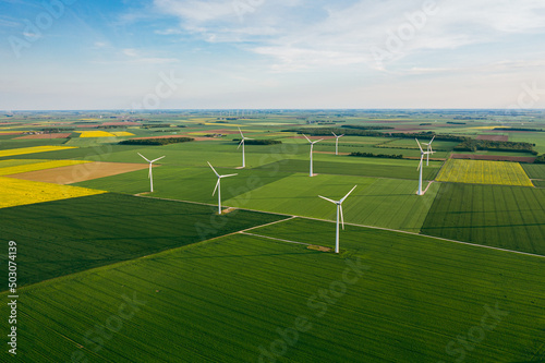 Wind Turbines Windmill Energy Farm. Wind turbines on sunny morning. Windmills wind turbines farm power generators against landscape against blue sky in beautiful nature. Aerial. 
