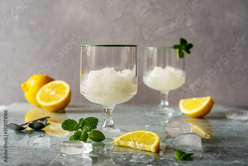 Wall Mural Lemon sorbet in two glasses with lemons, ice cubes, mint leaves on grey backgrou