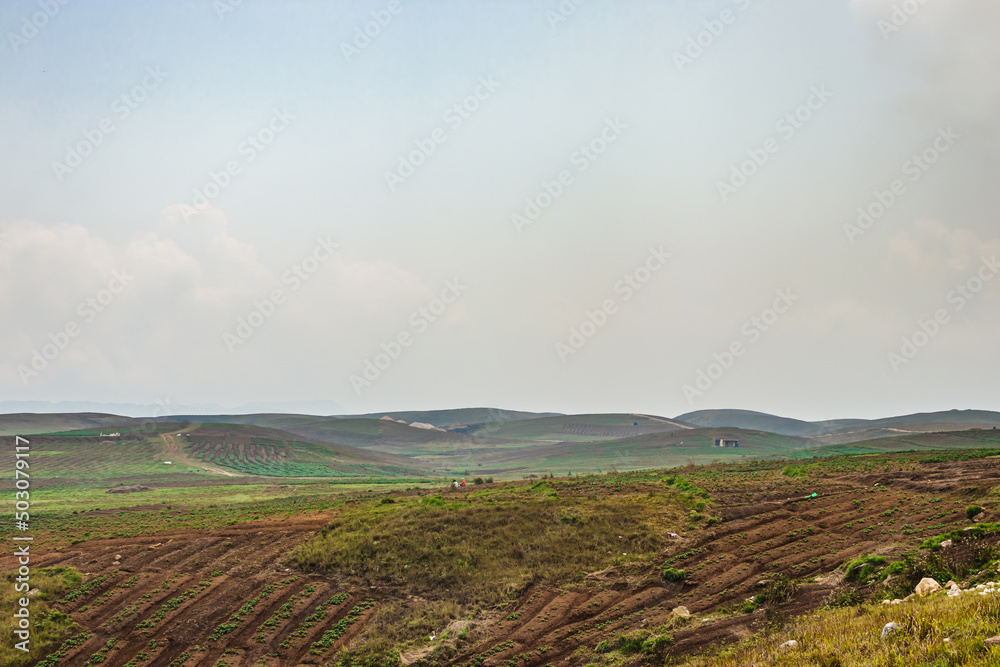 mountainside agriculture farming fields with bright blue sky at morning from flat angle