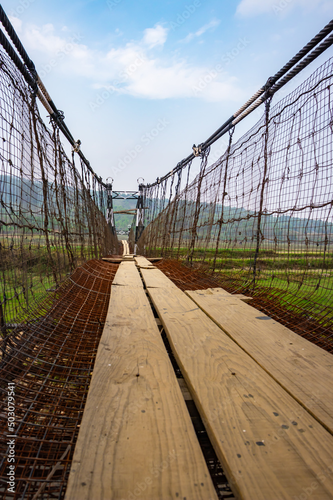 Fototapeta premium isolated old rusty iron suspension bridge with misty flat sky background at morning
