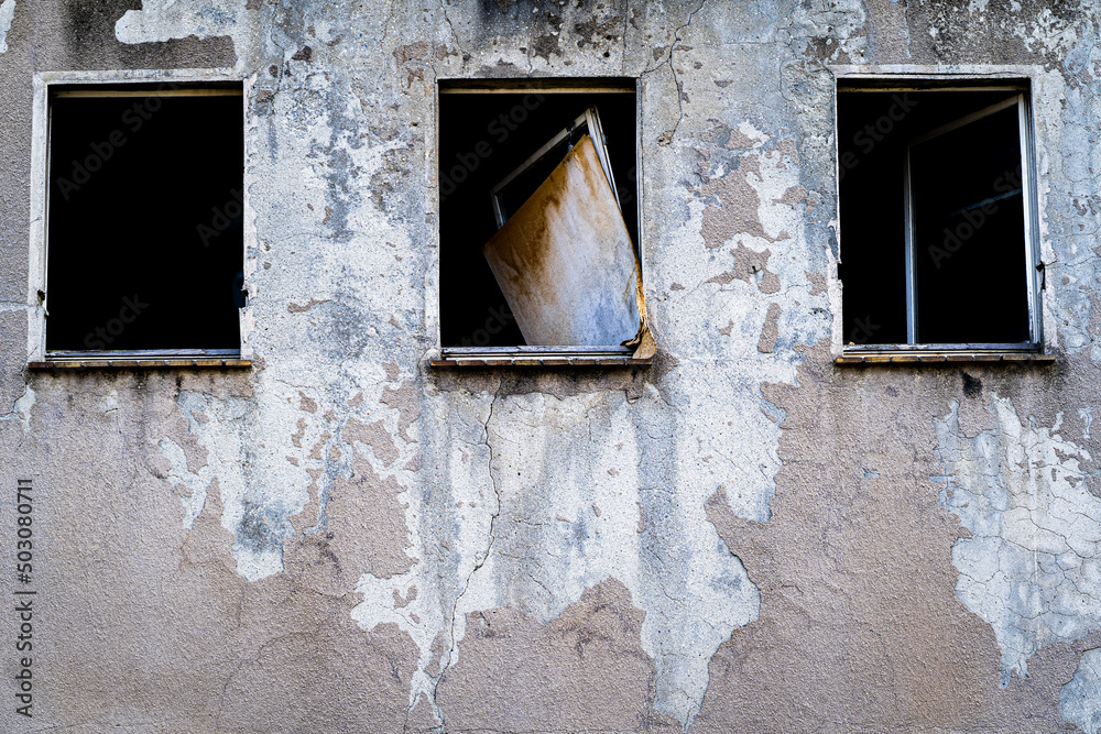 stary opuszczony budynek z rozbitymi oknami i zdartą farbą ze ściany - obrazy, fototapety, plakaty 