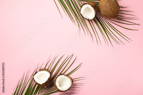 Summer concept. Top view photo of tropical fruits coconuts and palm leaves on isolated pastel pink background with copyspace