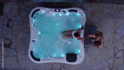 Romantic young couple relaxing in the hot tub with lights