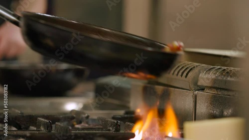 Fiery flambe in a skillet, capturing the art of cooking in a rustic kitchen at dusk