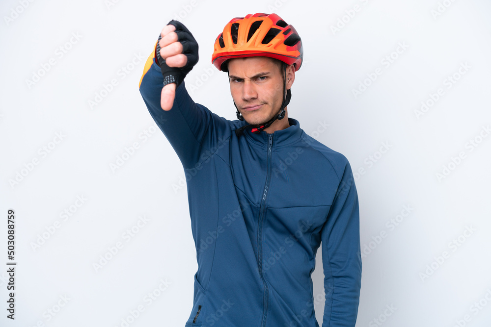 Fototapeta premium Young cyclist caucasian man isolated on white background showing thumb down with negative expression