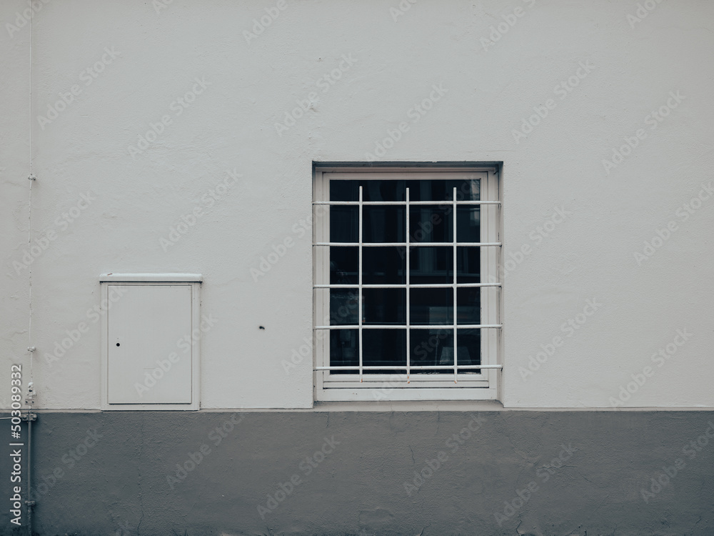 minimalistsche Fassade mit vergittertem Fenster 