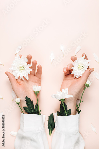 Creative image of beautiful groomed female hands with white summer flowers, isolated on pastel pink color background wall in minimalist style. Concept template feminine blog, social media, beauty