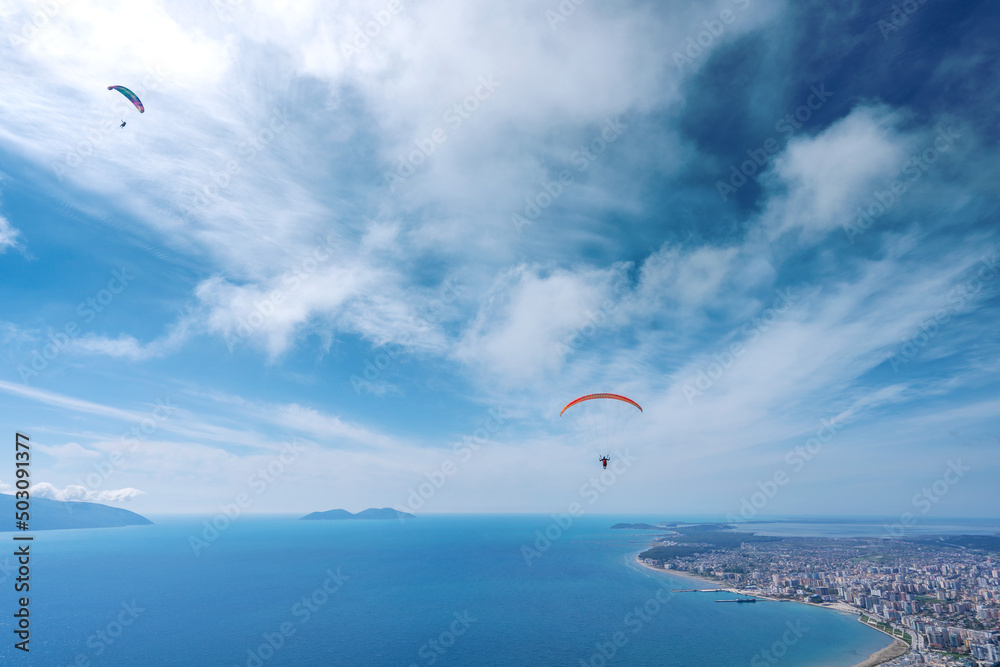 Athlete paragliding against the backdrop of a cloudy sky over the city on a summer day. Albania Athlete paragliding against the backdrop of a cloudy sky over the city on a summer day. Albania