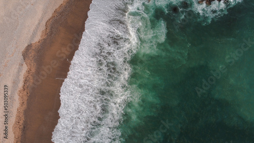 Aerial view on the beach with aquamarine sea and waves breaking on the beach
