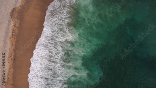 Aerial view on the beach with aquamarine sea and waves breaking on the beach