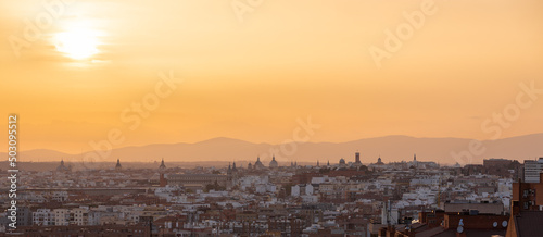 An amazing warm sunset over the skyline of Madrid with views on the mountain range, 
Sierra de Guadarrama on the horizon, seen from las siete tetas on Cerro Tio Pio hill side. photo