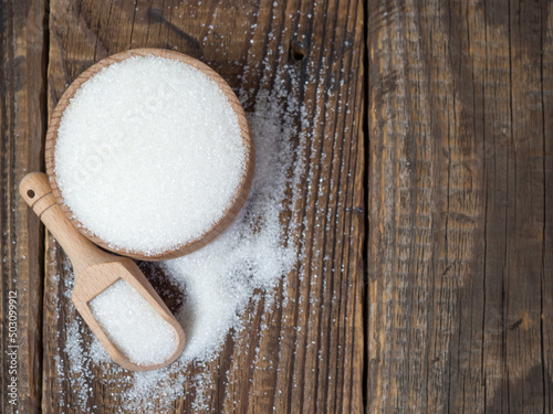 Stack of sugar cubes and granulated sugar in a wooden scoop
