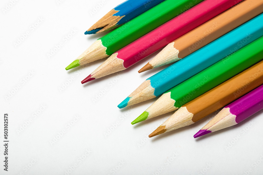 close up of vivid coloured pencils entering the left of the frame on a white background copy space from above close up of vivid coloured pencils entering the left of the frame on a white background copy space from above