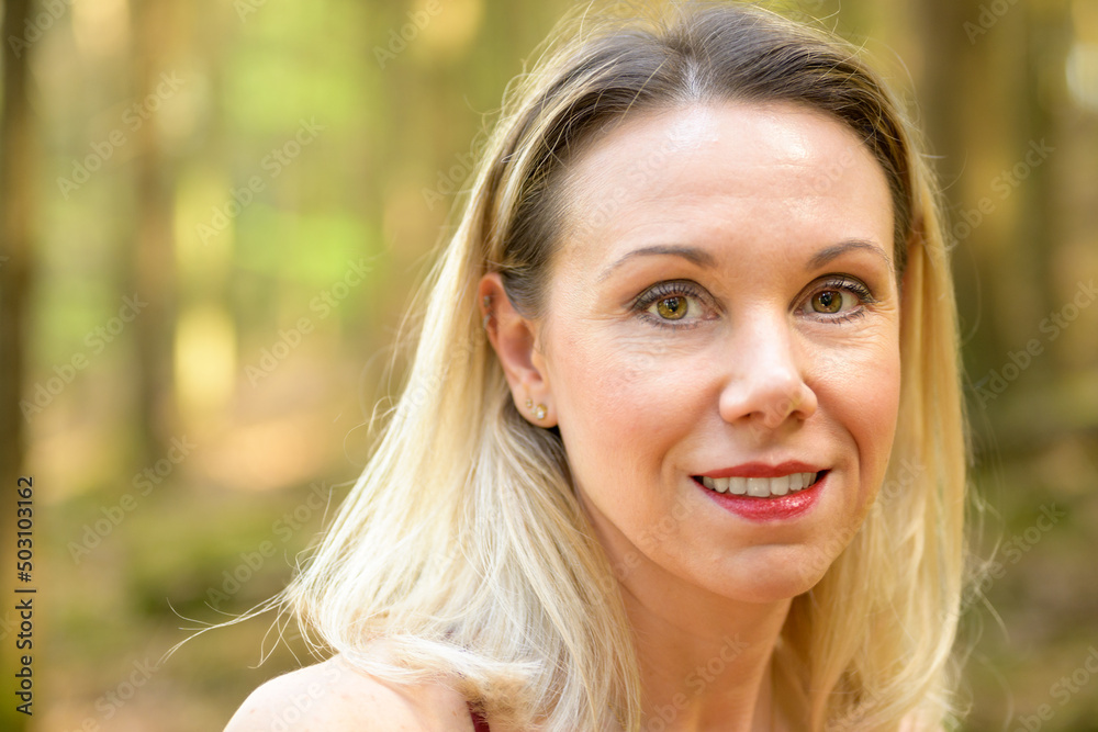 Blond smiling woman with light brown eyes.