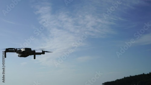 Flying drone in the air against the background of a blue sky with a slight cloudiness. High quality 4k footage