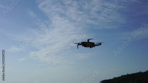 Flying drone in the air against the background of a blue sky with a slight cloudiness. High quality 4k footage