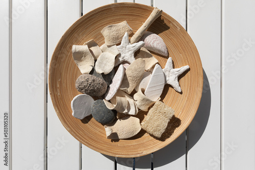 Overhead shot of wooden plate with rocks inside on white wooden background