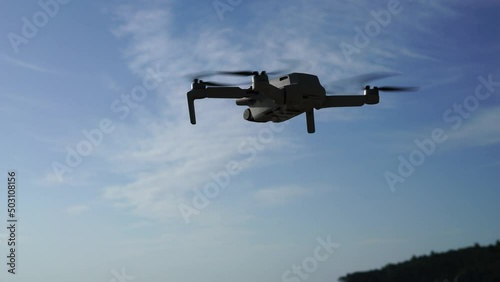 Flying drone in the air against the background of a blue sky with a slight cloudiness. High quality 4k footage