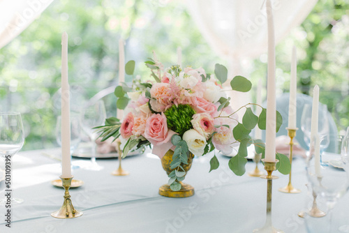 Wedding decor in blue. Banquet tables decorated bouquet with peonies on the tables are pink plates, glasses and candles