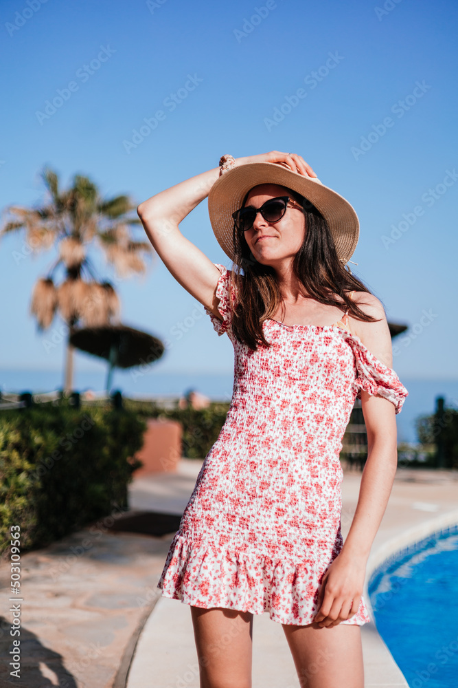 vertical view of beautiful woman relaxing next to the pool of a tropical resort