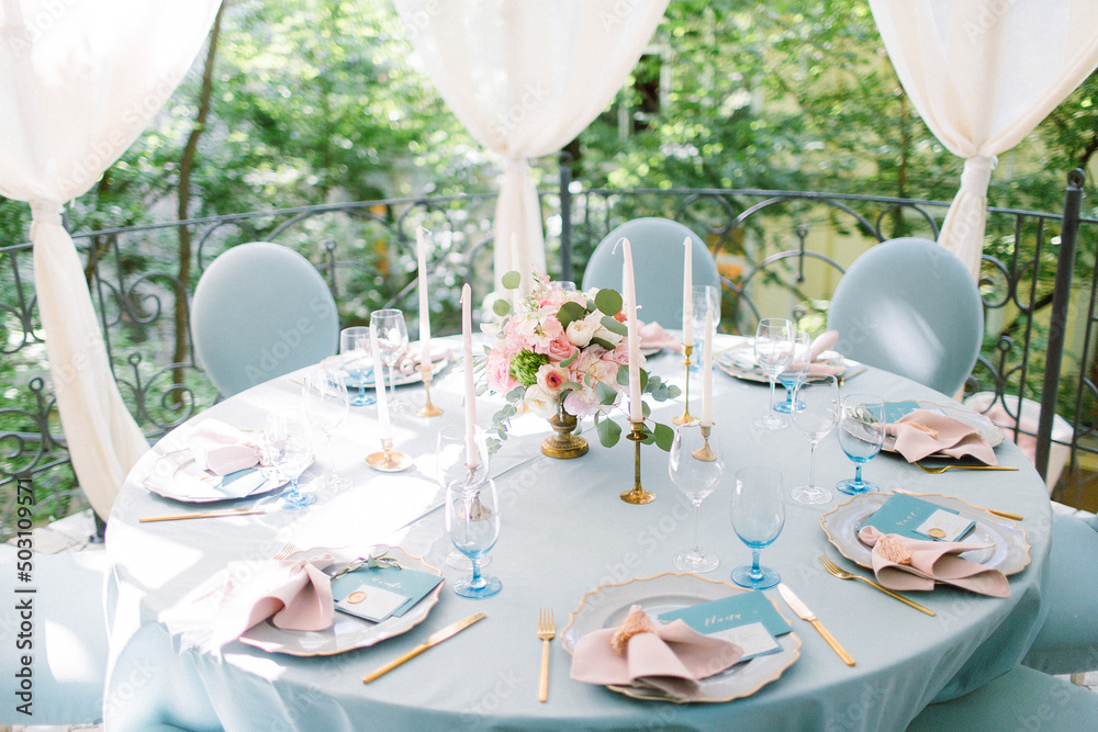 Wedding decor in blue. Banquet tables decorated bouquet with peonies on the tables are pink plates, glasses and candles