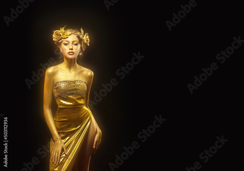 Portrait Beauty fantasy woman queen, face in gold paint. Golden shiny glowing skin. Fashion model girl, image goddess. Glamorous crown, wreath roses jewellery accessories. Professional metallic makeup photo