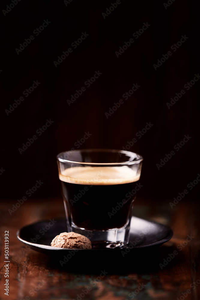 Fototapeta premium Coffee in glass cup on dark wooden background. Copy space.