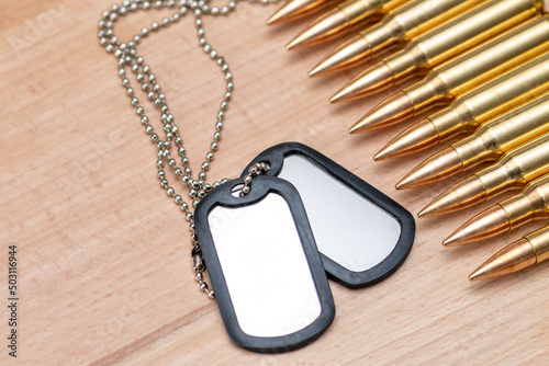 A row of cartridges with 7.62 caliber bullets for a Kalashnikov assault rifle on a textured background, an army identification badge, close-up, selective focusing. Concept: conscription, military recr photo