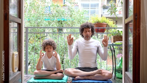 Obraz na płótnie father and 7-year-old son boy do yoga relaxing exercises at home in the balcony with the arrival of spring they get ready for summer - meditation outside of the window w salonie