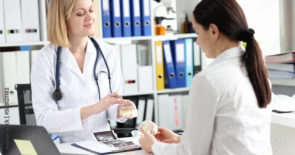 Doctor plastic surgeon shows silicone breast implants to woman Doctor plastic surgeon shows silicone breast implants to woman