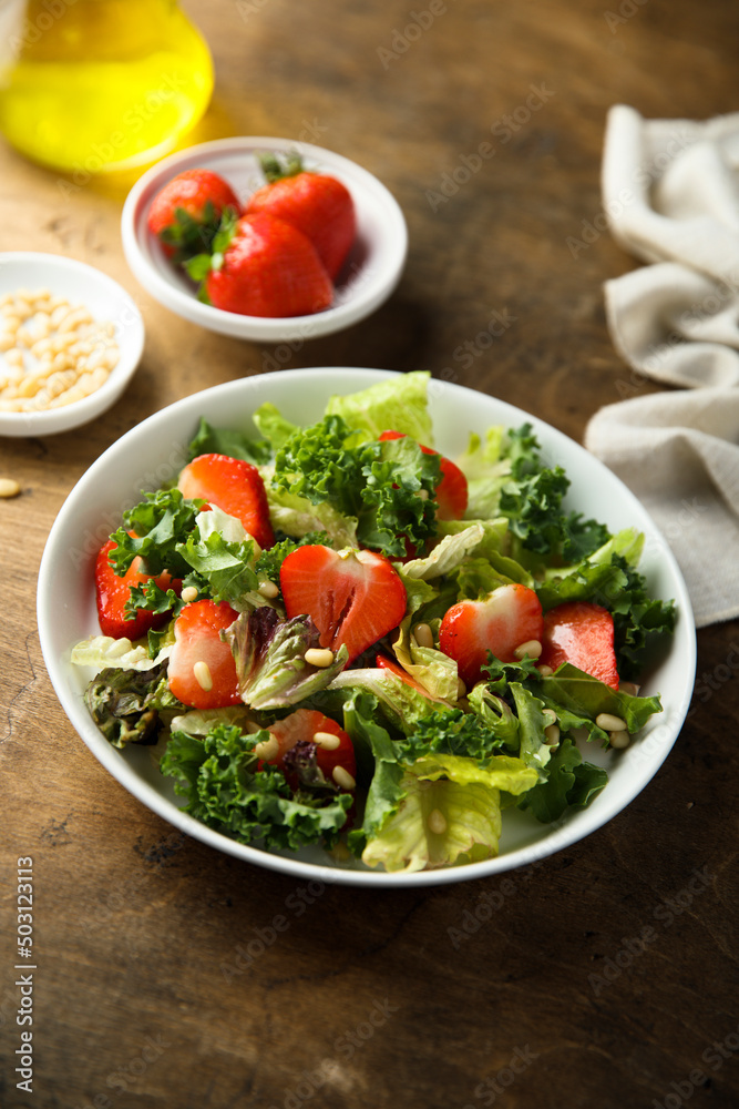 Healthy green salad with strawberry and pine nuts