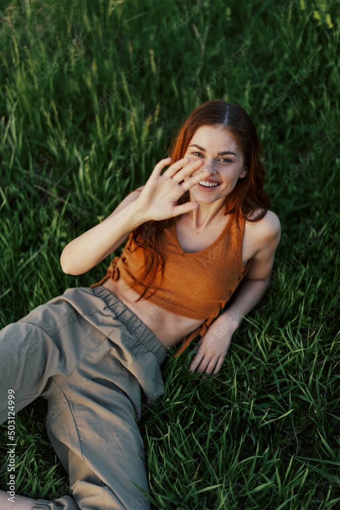 The view from above is a woman lying on the green grass in the park and relaxing in nature smiling and enjoying life. The concept of a healthy lifestyle The view from above is a woman lying on the green grass in the park and relaxing in nature smiling and enjoying life. The concept of a healthy lifestyle