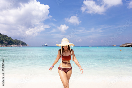 woman wearing a straw hat and orange bikini relax on the beach with beautiful blue sky.at Similan island Phuket Thailand , summer vacation concept