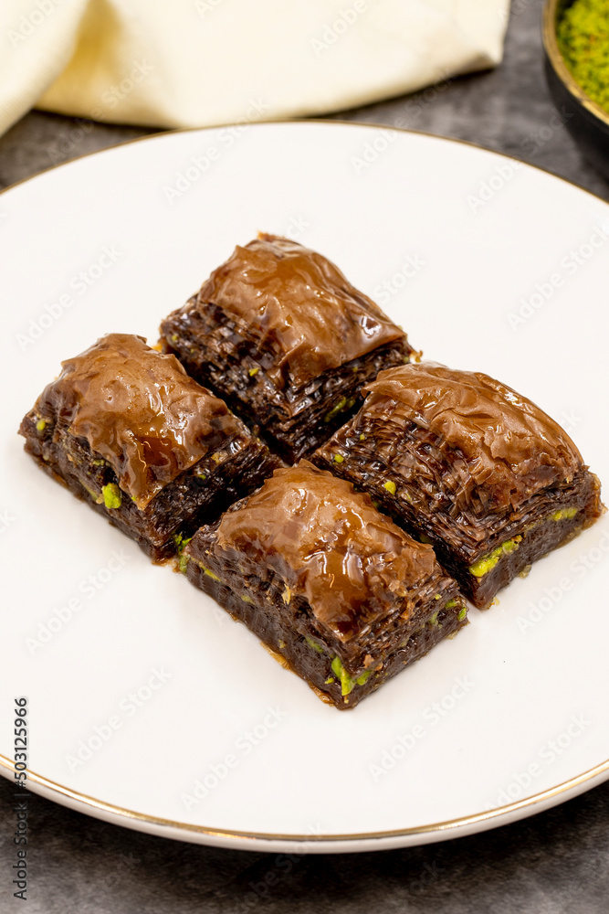 Chocolate baklava. Chocolate baklava with pistachio on dark background. Mediterranean cuisine delicacies. Close-up. local name cikolatali baklava Chocolate baklava. Chocolate baklava with pistachio on dark background. Mediterranean cuisine delicacies. Close-up. local name cikolatali baklava