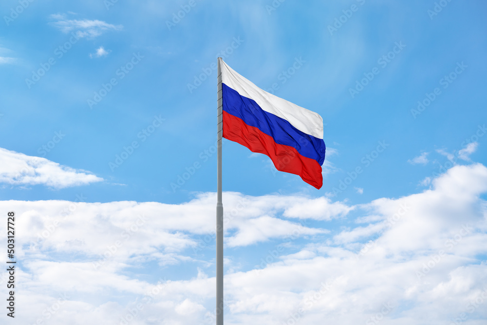 Russian white-blue-red flag is waving in front of blue sky and clouds Russian white-blue-red flag is waving in front of blue sky and clouds