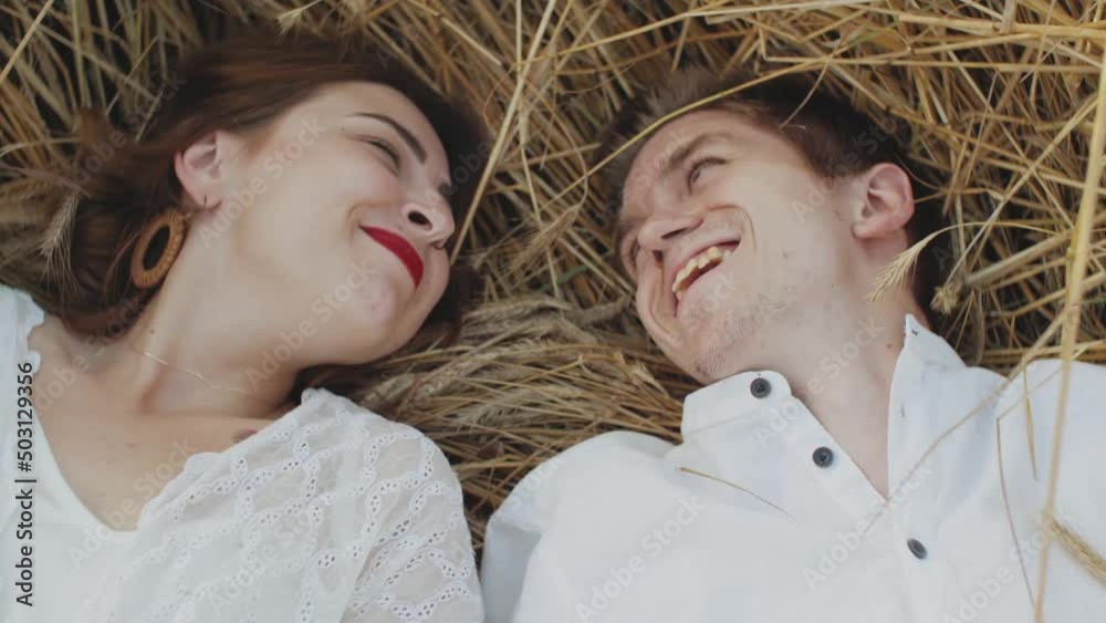 beautiful red-haired Caucasian women in white dress on field of spikelets posing, smiling, the girl takes the brown hat from the guy and indulges. beautiful red-haired Caucasian women in white dress on field of spikelets posing, smiling, the girl takes the brown hat from the guy and indulges.