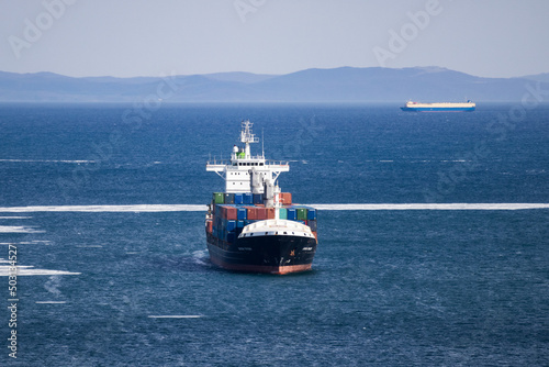 A merchant ship in the blue sea transports containers.