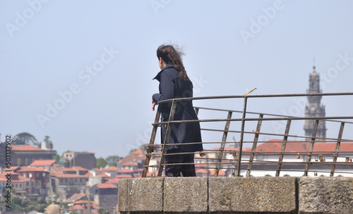 Pessoa do sexo feminino num miradouro da cidade do Porto em Portugal a contemplar as vistas, Torre dos Clérigos em desfoque - serra do pilar, cabelo ao vento, Vila Nova de Gaia photo