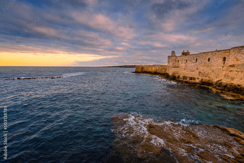 Sunset over the sea with cloudy sky with Maniace Castle in Ortigia Sunset over the sea with cloudy sky with Maniace Castle in Ortigia