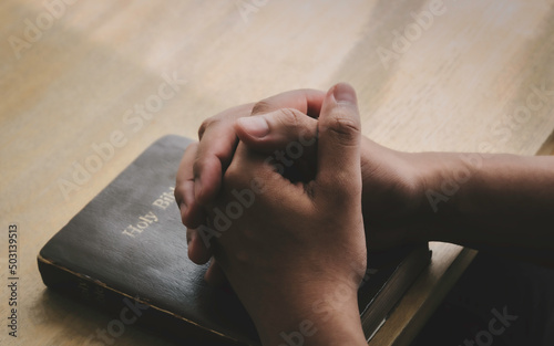 Obraz na plátně Human hands praying for God's blessings on a wooden table for a better life