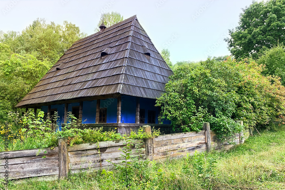 Authentic traditional culture in architecture and life. Old wooden buildings and rural fence in summer day.