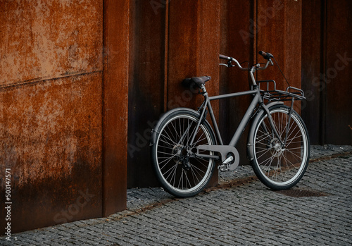 Modern parked bicycle near the wooden walls on the textured grey ground photo