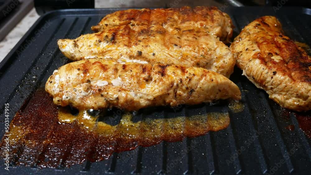 Delicious juicy chicken steak seasoned with herbs and spices is fried in a grill. Barbecue party.