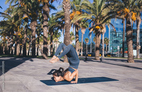 Strong Asian 20s woman in active wear standing in inverse yoga pose breathing and reaching zen, concentrated female with slim figure have hatha morning training in stretching asanas outdoors