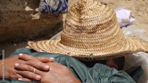 Male relaxing on the sand with the straw hat photo