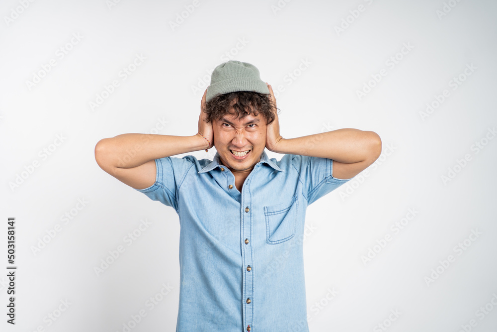 Stressed asian young man cover his ear does not want to hear anything over isolated background