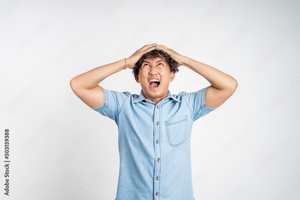 Stressed asian young man holding his head over isolated background Stressed asian young man holding his head over isolated background
