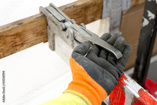 Foto Closeup of a driver's hand fastening securely a truckload using an aluminum bar