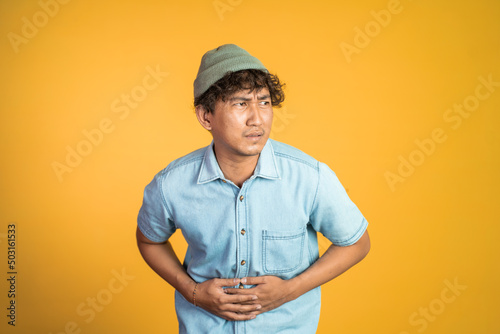 Vászonkép asian young man having stomach ache on background isolated