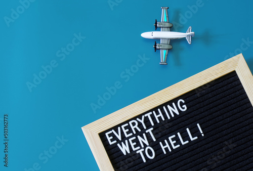 Toy passenger plane next to a felt board that says everything went to hell. The concept of depression, fatigue, disappointment and relocation, or going on vacation. Blue background